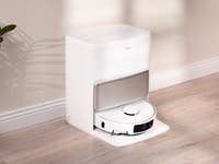 Eine Mova P50 Pro Ultra Robotersauger-Dockingstation in einem modernen Innenraum mit Holzboden und einer Pflanze in der Nähe.