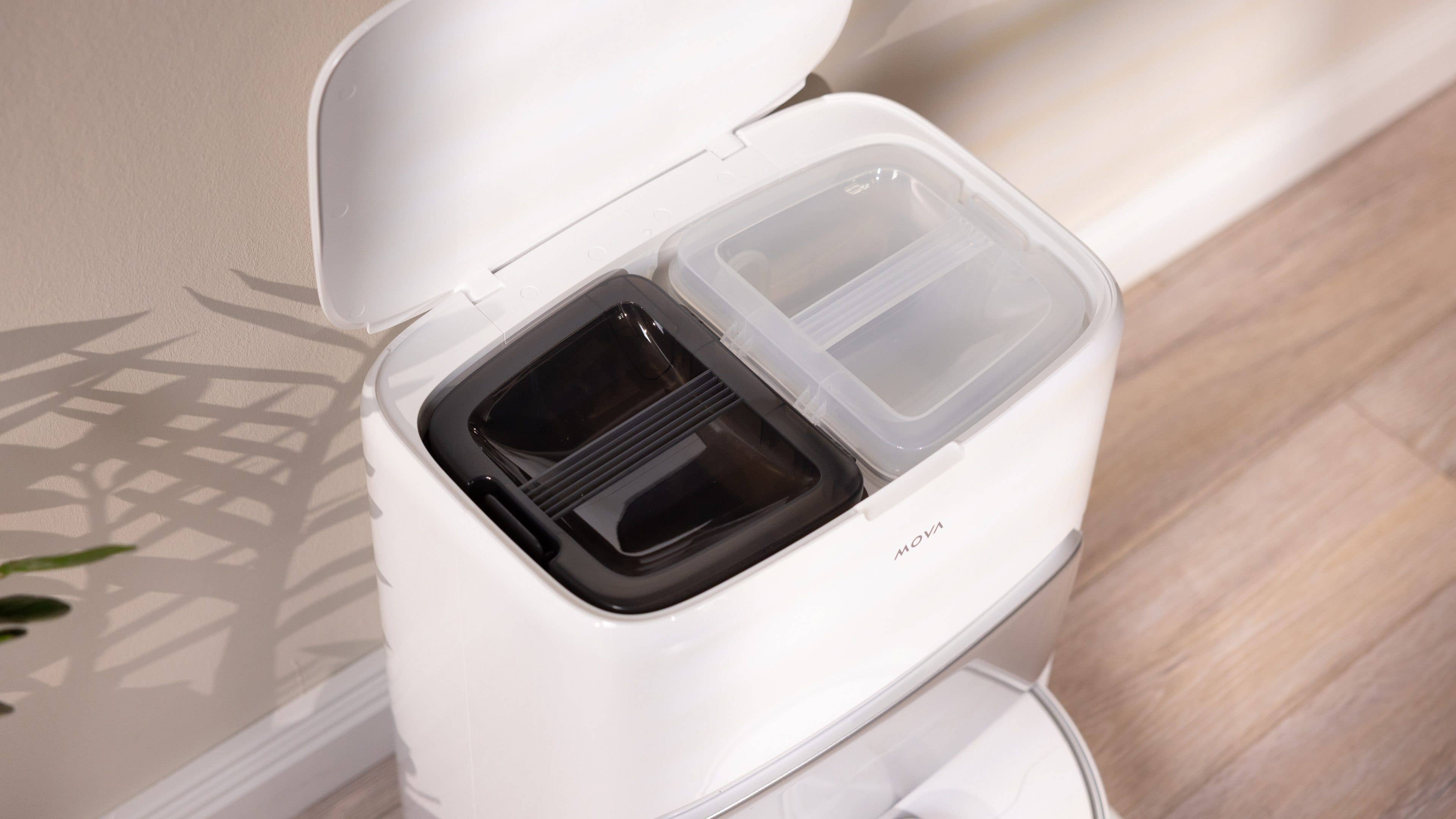 Ein weißer Behälter mit zwei Fächern, eines dunkel und eines klar, mit offenem Deckel.