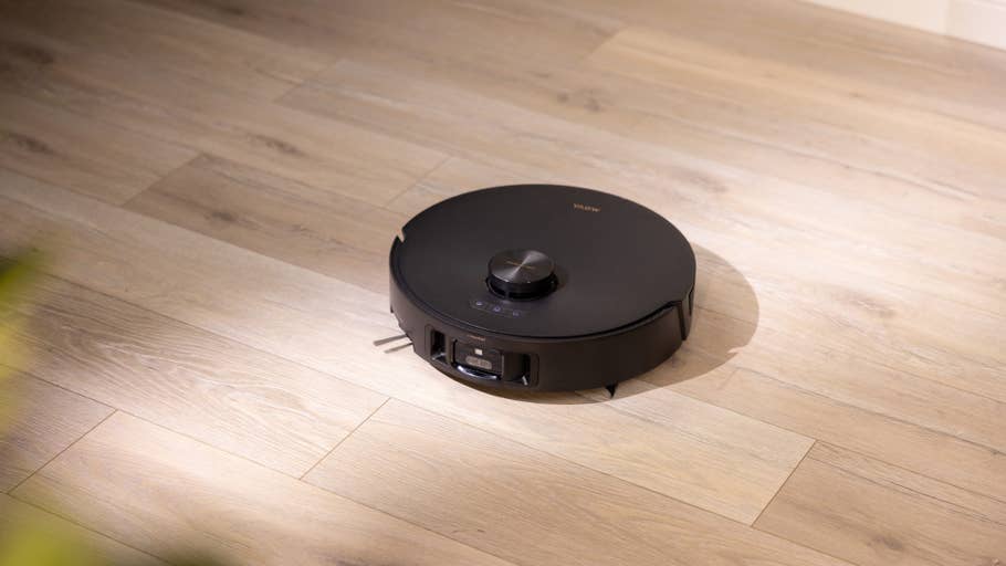 Ein schwarzer Roboterstaubsauger auf hellem Holzboden.