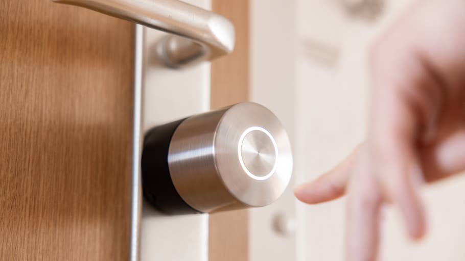 Nahaufnahme eines Nuki Smart Lock Pro an einer Tür mit einer Hand, die sich ihm nähert.