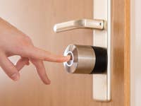 Eine Hand steht kurz davor, ein Nuki Smart Lock Pro an einer Tür zu berühren.