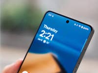 Nahaufnahme eines Smartphones, das die Uhrzeit 2:21 und das Datum 9. Januar mit klarem blauen Hintergrund zeigt.