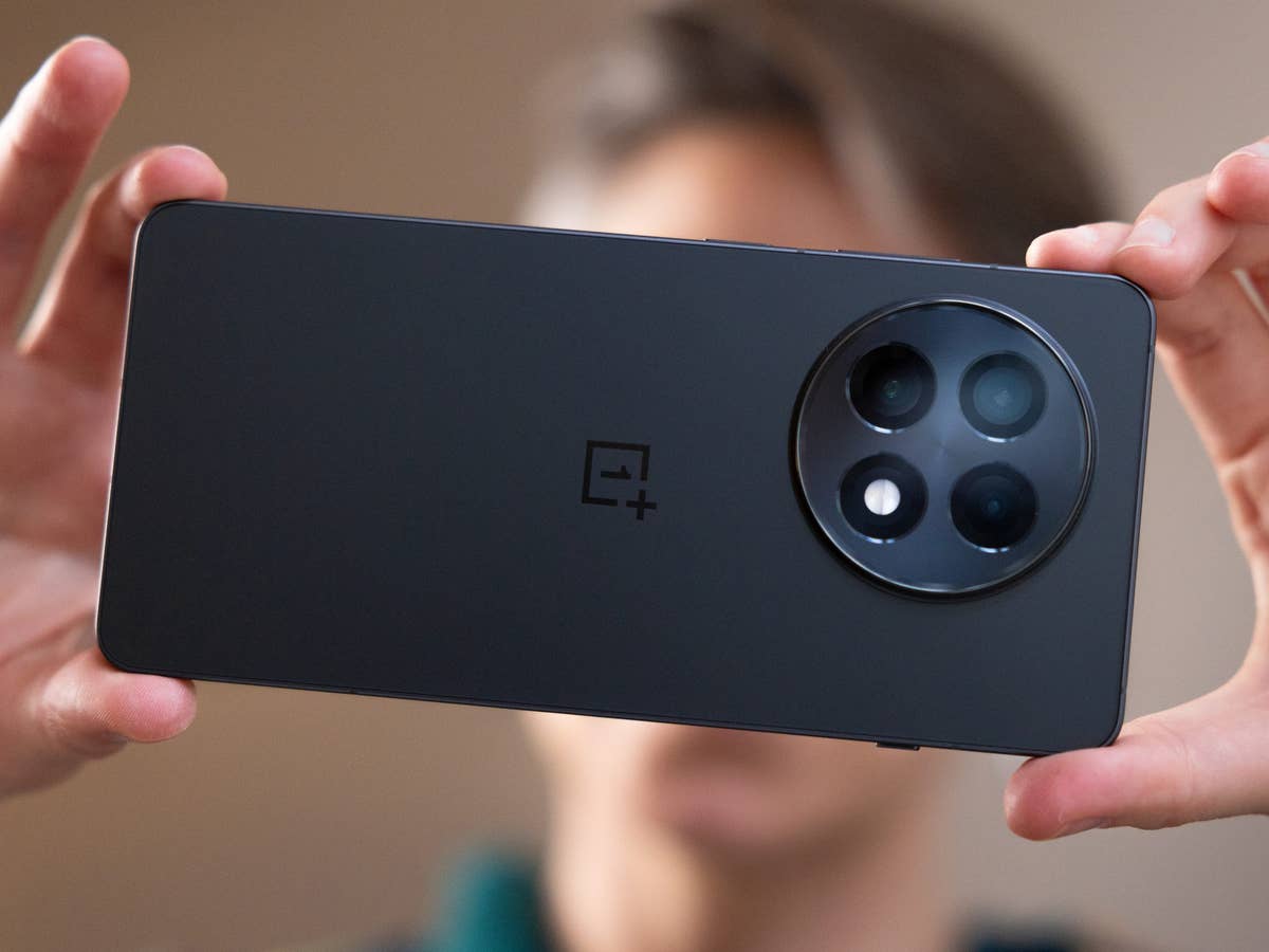 Eine Person hält die Rückseite eines OnePlus 13R-Smartphones und zeigt das Kameradesign.