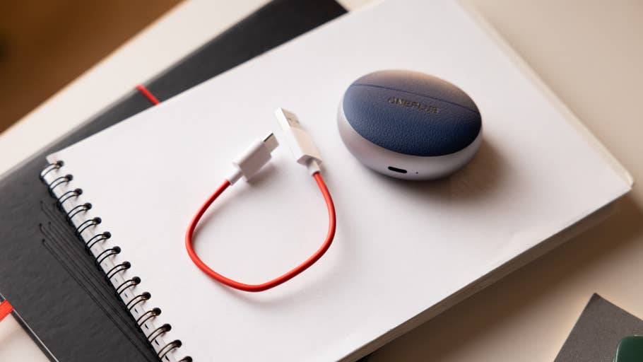 Ladecase der OnePlus Buds Pro 3 mit einem roten USB-Kabel auf einem Notizbuch.