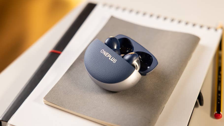 Ladecase der OnePlus Buds Pro 3 auf einem Notizbuch mit einem Bleistift.