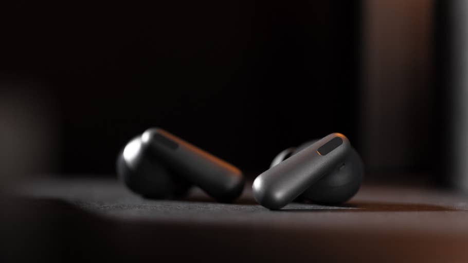 Zwei schwarze kabellose Kopfhörer liegen auf einer Fläche mit einem dunklen Hintergrund.