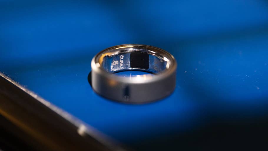 Nahaufnahme eines Oura Ring 4 auf einer blauen Oberfläche, die sein elegantes Design zeigt.