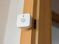 Ein Philips Hue Bewegungssensor, der an einem Holzrahmen montiert ist.