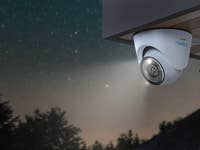 Überwachungskamera an Häuserwand, im Hintergrund Nachthimmel