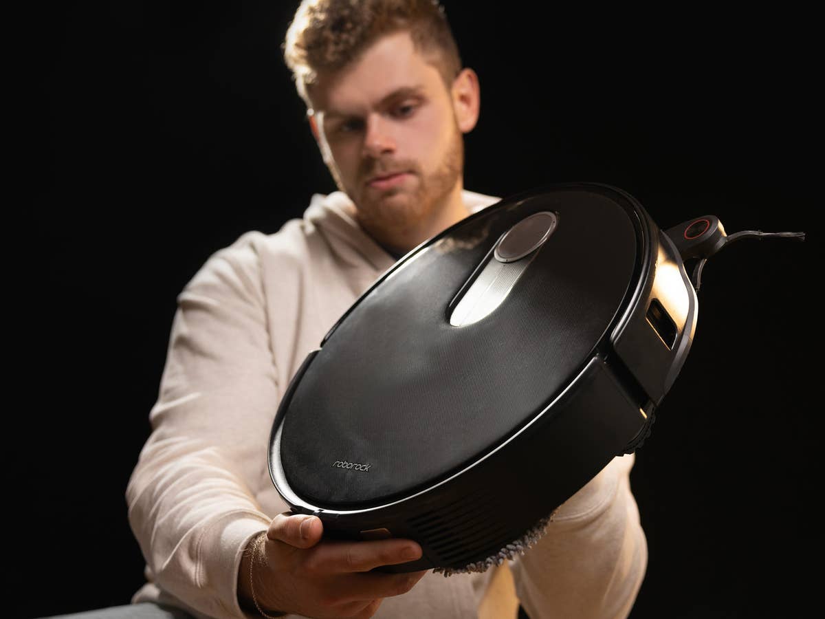 Roborock Qrevo Slim im Vordergrund, gehalten von einer Person