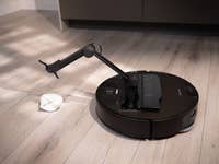 Ein Roborock Saros Z70 Saugroboter auf einem Holzboden neben einem Tuch.