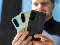 Eine Person hält drei Samsung Galaxy A-Serie-Smartphones in verschiedenen Farben.