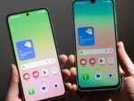 Zwei Samsung-Smartphones der Galaxy A-Serie in der Hand, die bunte Bildschirme mit Wetterinformationen zeigen.
