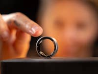 Eine Nahaufnahme eines Samsung Galaxy Rings auf einem Ständer, mit einer Hand, die ihn im Hintergrund berührt.