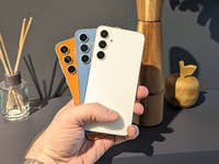 Drei verschiedenfarbige Modelle des S23 FE vor einem Küchenregal in der Hand gehalten