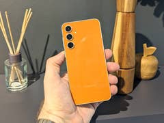 Galaxy S23 FE wird mit Rückseite nach vorne vor einem Küchenregal gehalten