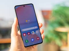 Eine Person hält ein Samsung Galaxy S24 FE-Smartphone, das eine Wetter-App mit einer Temperatur von 34 °C anzeigt.