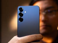 Eine Person hält ein Samsung Galaxy S25 Plus Smartphone mit einem blauen Farbverlauf und drei Kameralinsen.