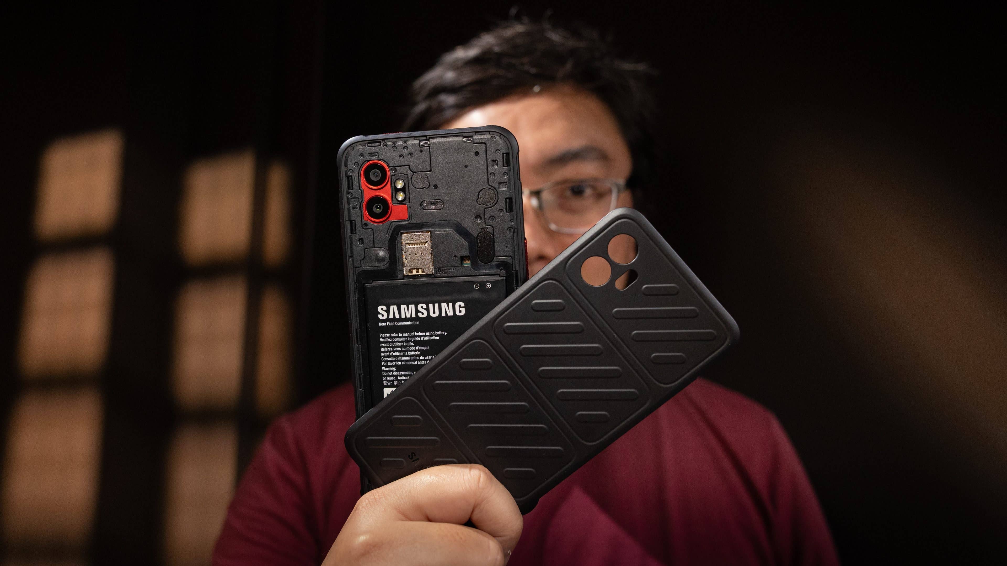 Eine Person hält ein Samsung Galaxy XCover 7 Pro Smartphone und seine Schutzhülle.