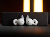 Weiße Sony LinkBuds liegen auf einer schwarzen Box mit sanfter Beleuchtung im Hintergrund.