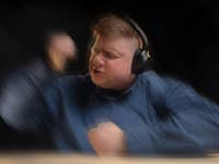 Eine Person mit Kopfhörern gestikuliert leidenschaftlich, während sie Musik hört.