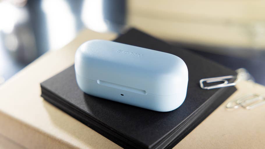 Hellblaues „Sony WF-C510“-Ladecase liegt auf schwarzen und braunen Notizblöckn mit Büroklammern