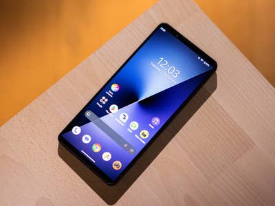 Sony Xperia 1 VIII Smartphone auf einer Holzoberfläche, zeigt den Startbildschirm mit Uhrzeit und App-Icons.