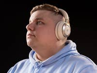 Eine Person mit Anker Soundcore Space One Kopfhörern, die nachdenklich nach oben schaut, vor einem dunklen Hintergrund.