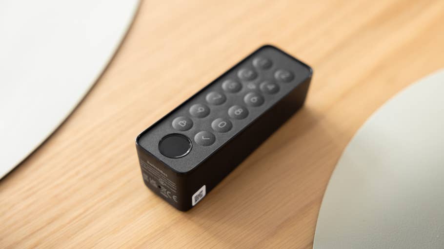 Ein schwarzes SwitchBot Lock Ultra Touch Combo-Gerät mit einem Ziffernblock auf einer Holzoberfläche.