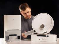 Ein Mann untersucht den SwitchBot S10 Saugroboter und seine Dockingstation.