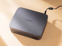 UGREEN Nasync DXP480T Plus-Gerät mit einem Stromkabel auf einer beigen Oberfläche.