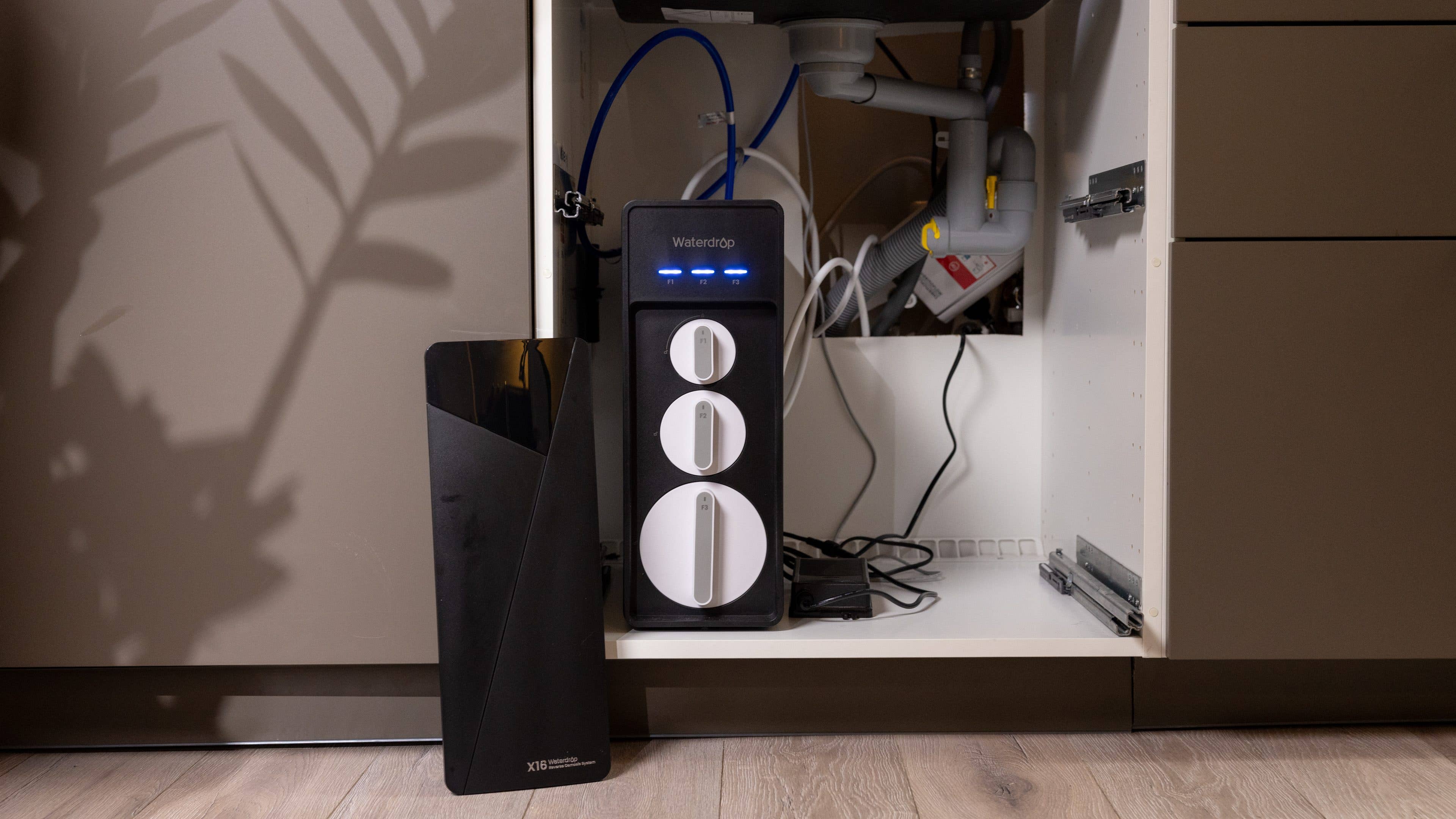 Ein Wasserfiltersystem, das unter einer Küchenspüle installiert ist, mit einem schwarzen Gerät daneben.
