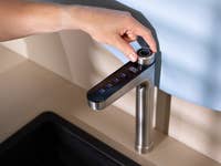 Eine Hand passt einen modernen Küchenwasserhahn mit Touch-Bedienelementen und elegantem Design an.