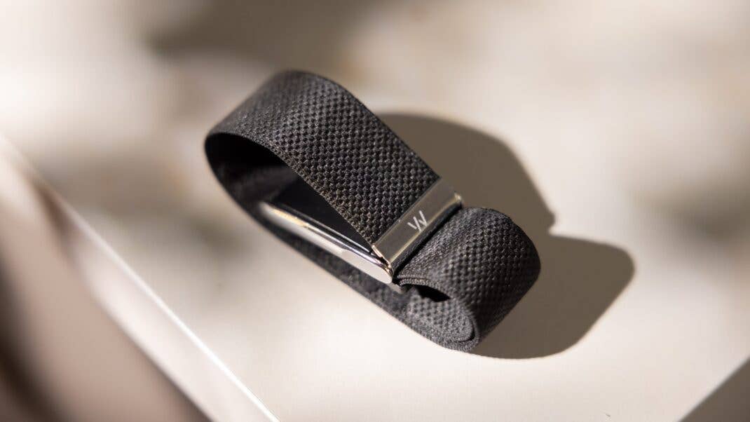 Ein schwarzes, strukturiertes Armband mit silbernem Verschluss, auf einer hellen Oberfläche.