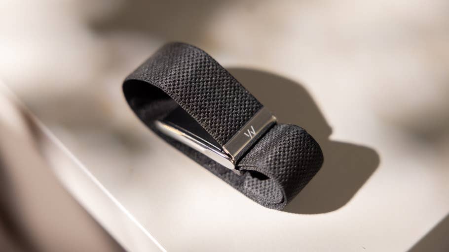 Ein schwarzes, strukturiertes Armband mit silbernem Verschluss, auf einer hellen Oberfläche.