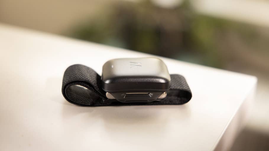 Ein schwarzes tragbares Gerät mit einem Riemen, das auf einer weißen Oberfläche liegt.