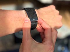 Eine Person passt einen Whoop MG-Sensor-Fitness-Tracker an ihrem Handgelenk an.
