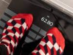 Füße mit rot-weißen gemusterten Socken stehen auf einer Withings Body Scan-Waage, die 62,80 kg anzeigt.