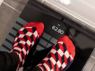 Füße mit rot-weißen gemusterten Socken stehen auf einer Withings Body Scan-Waage, die 62,80 kg anzeigt.