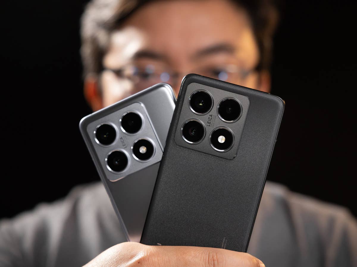 Eine Person hält zwei Xiaomi 14T Pro-Smartphones, eines in Grau und eines in Schwarz, vor einem dunklen Hintergrund.