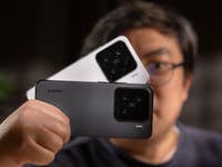 Eine Person hält zwei Xiaomi 15 Smartphones, eines weiß und eines schwarz, mit sichtbaren Kameralinsen.