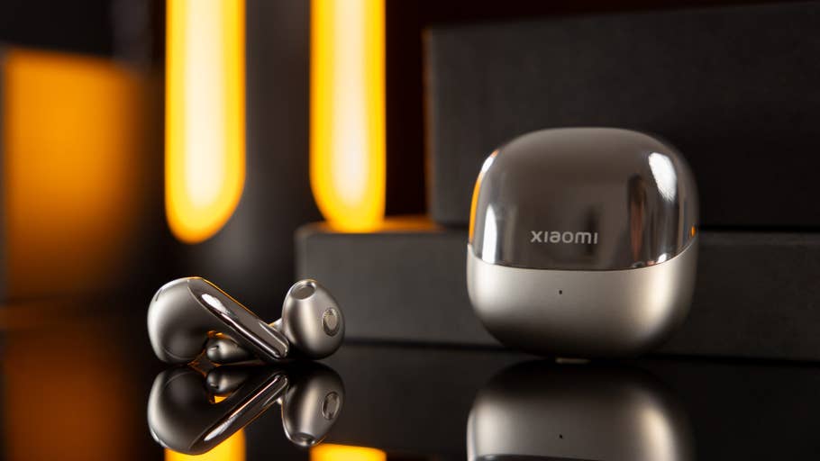 Drahtlose Kopfhörer Xiaomi Buds 5 neben ihrer Ladebox auf einer reflektierenden Oberfläche.