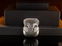 Xiaomi Buds 5 drahtlose Ohrhörer auf einer dunklen Oberfläche mit sanfter Beleuchtung.