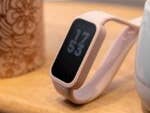 Ein Xiaomi Smart Band 9 Active in rosa, das um 17:53 auf einer Holzoberfläche neben einer gemusterten Tasse angezeigt wird.