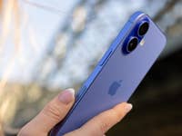 Eine Person hält ein blaues Apple iPhone 16, das die Dual-Kamera und das schlanke Design zeigt.