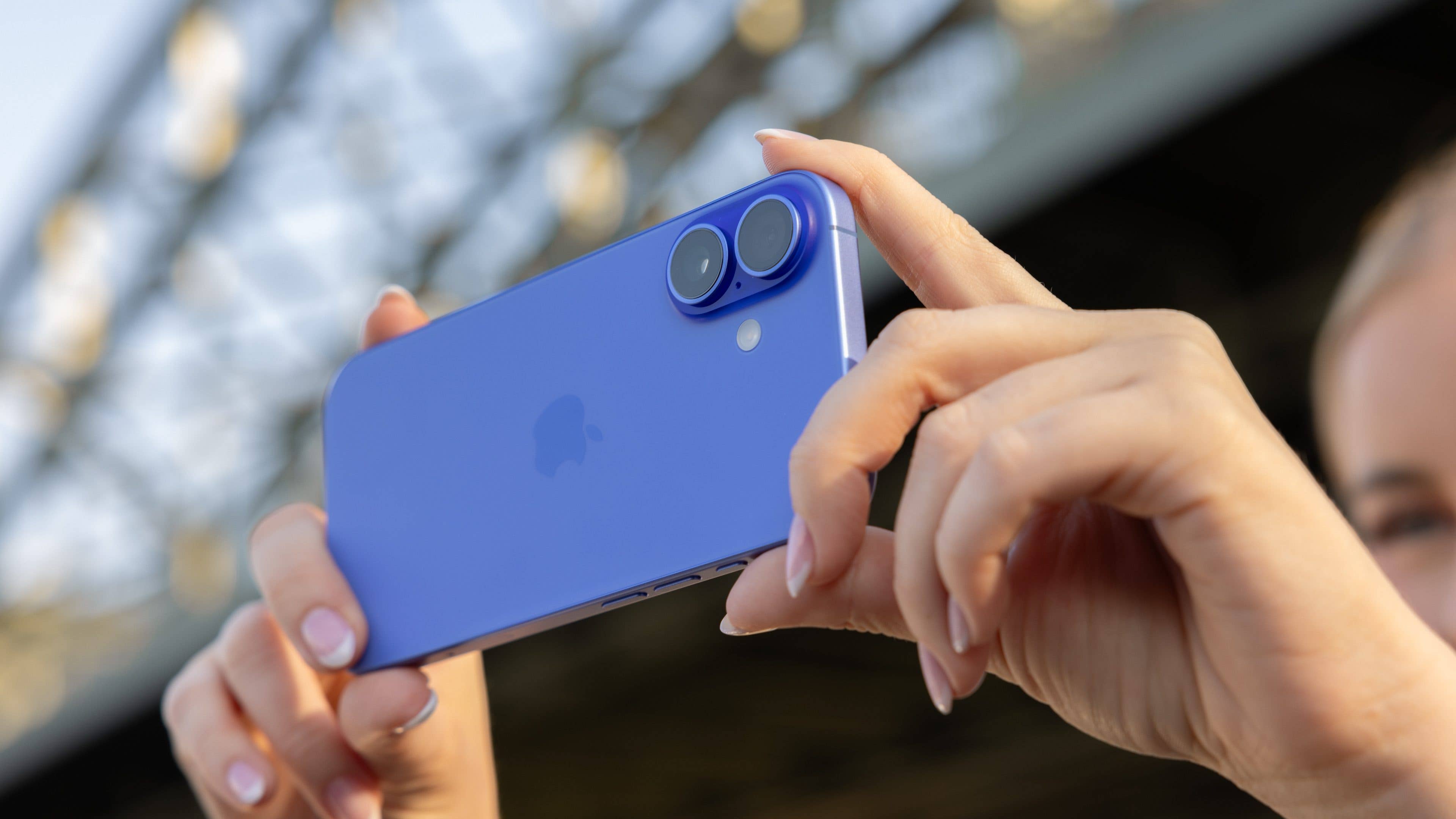 Eine Person hält ein blaues iPhone 16 mit Dual-Kameras in einer sonnigen Außenumgebung. Eine Person hält ein blaues iPhone 16 mit Dual-Kameras in einer sonnigen Außenumgebung.