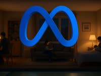 Ein blauer Unendlichkeitssymbol, das Meta darstellt, mit zwei Personen, die zu Hause in einem gemütlichen Ambiente Geräte verwenden.