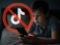Ein Junge verwendet ein Smartphone im Bett mit einem überlagerten 'kein TikTok'-Symbol.