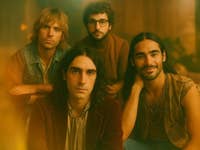 Bandporträt von vier Musikern mit warmem, vintage Ästhetik.