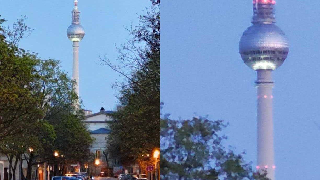 Ein hoher Turm mit einer kugelförmigen Spitze, die nachts beleuchtet ist, umgeben von Bäumen und Straßenlaternen.